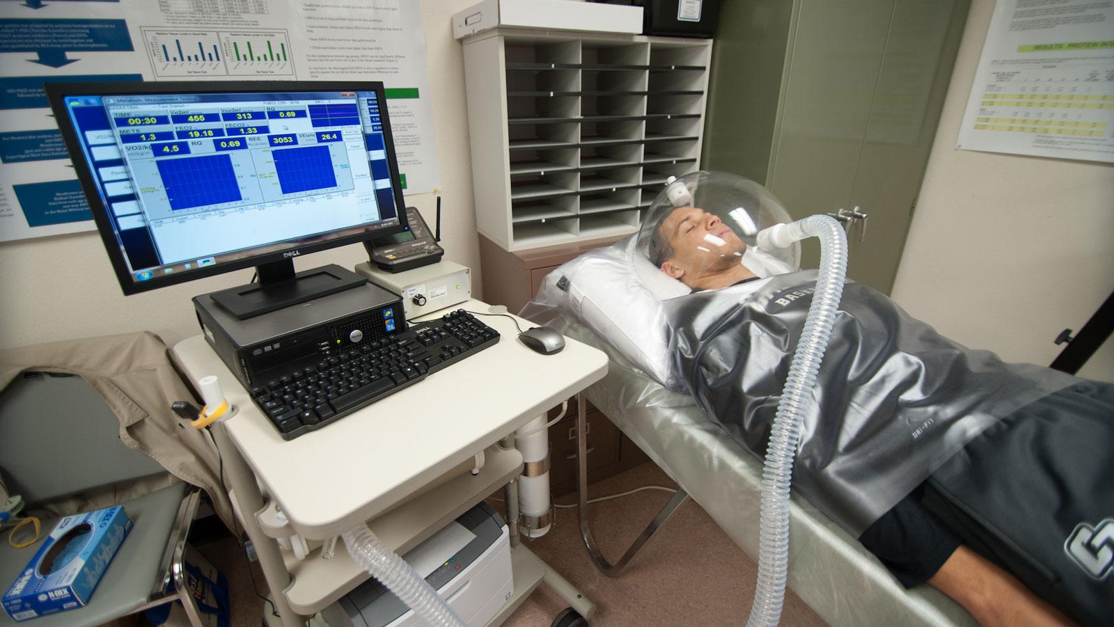 Individual undergoing metabolic testing while connected to monitoring equipment in a lab.